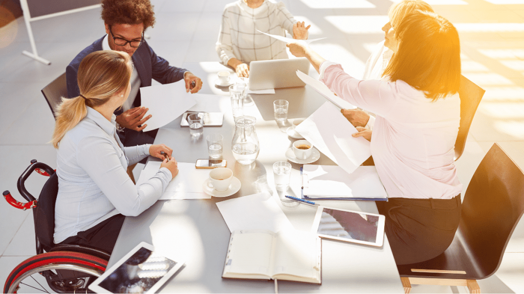 Team di lavoro diversificato composto da quattro donne di cui una sulla sedia a rotelle e un uomo nero. Attenzione ai temi di diversità, equità e inclusione