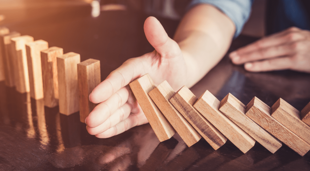 Uomo d’affari che posiziona un blocco di legno su una torre, concetto di controllo del rischio, pianificazione e strategia aziendale. Tono vintage.
