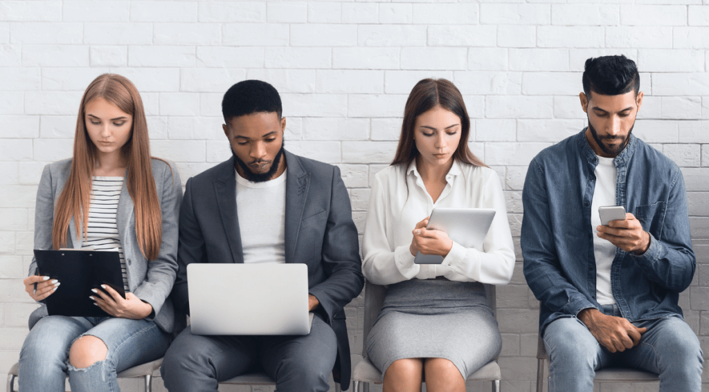 Candidati in attesa di un colloquio di lavoro, rappresentazione del fenomeno del job hopping tra giovani professionisti.