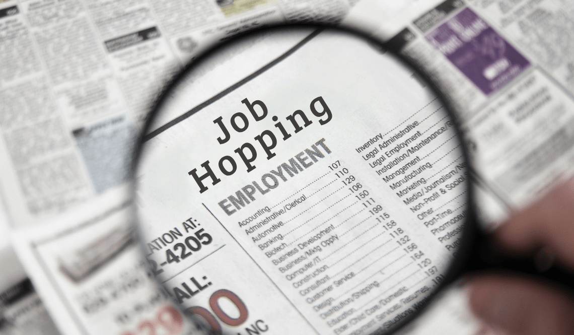 Lente d’ingrandimento su un annuncio di giornale con la scritta “Job Hopping”, concetto del cambio frequente di lavoro.