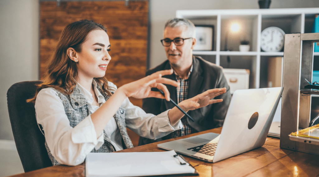 Giovane dipendente che spiega strumenti digitali a un collega senior, esempio pratico di reverse mentoring in azienda.