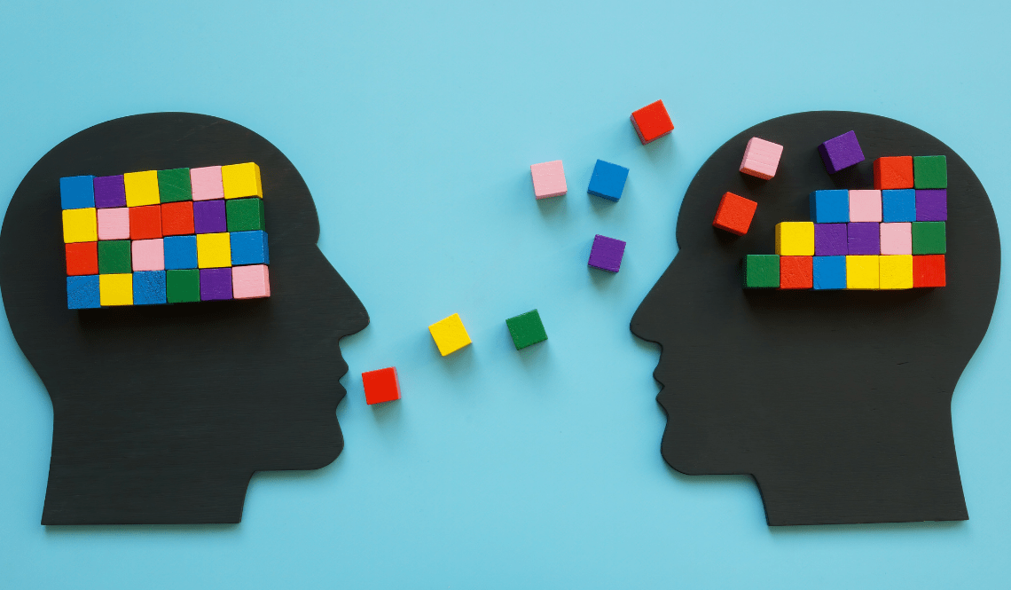 Due profili umani stilizzati che si scambiano blocchi colorati, simbolo del trasferimento di competenze nel reverse mentoring.