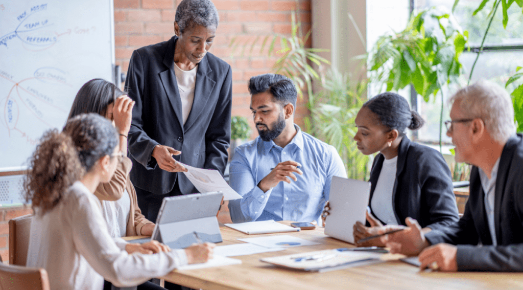 Riunione di un team aziendale con manager e colleghi che analizzano documenti, rappresentazione del ruolo HR nelle crisi aziendali.